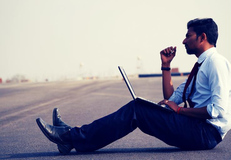 Muž, podnikateľ sedí na ceste, premýšľa a pracuje s notebookom.jpg